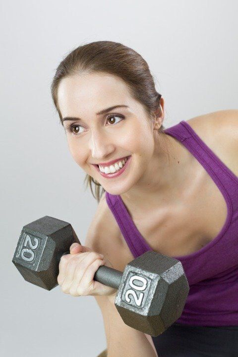 a girl with a dumbbell performs a weight loss exercise
